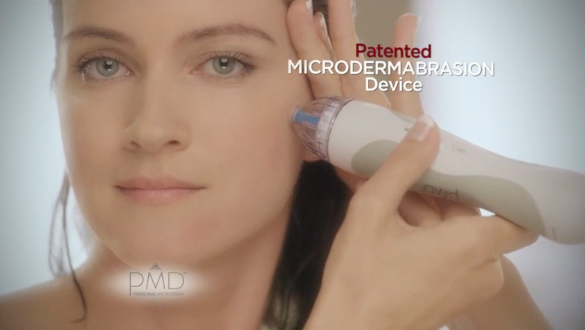 woman uses microderm abrasion device in mirror